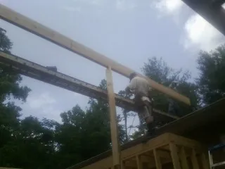 Carpenter setting a ridge beam over a new addition frame — Ice Dam Removal by Roofing Brothers in Gates
