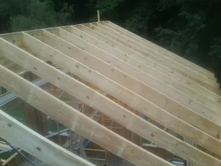 New roof rafters set over an addition before sheathing in Gates