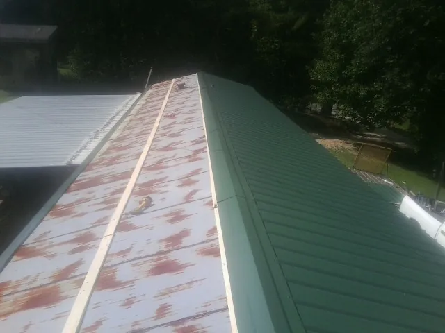 Old rusted panels beside newly installed green metal roofing — Wind Damage Roof Repair by Roofing Brothers in Gates
