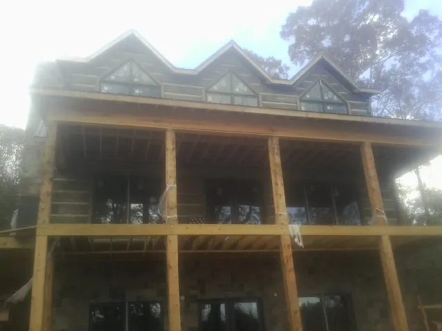 Dormers and porch framing on a large log home under construction — Roof Coating work by our crew in Gates