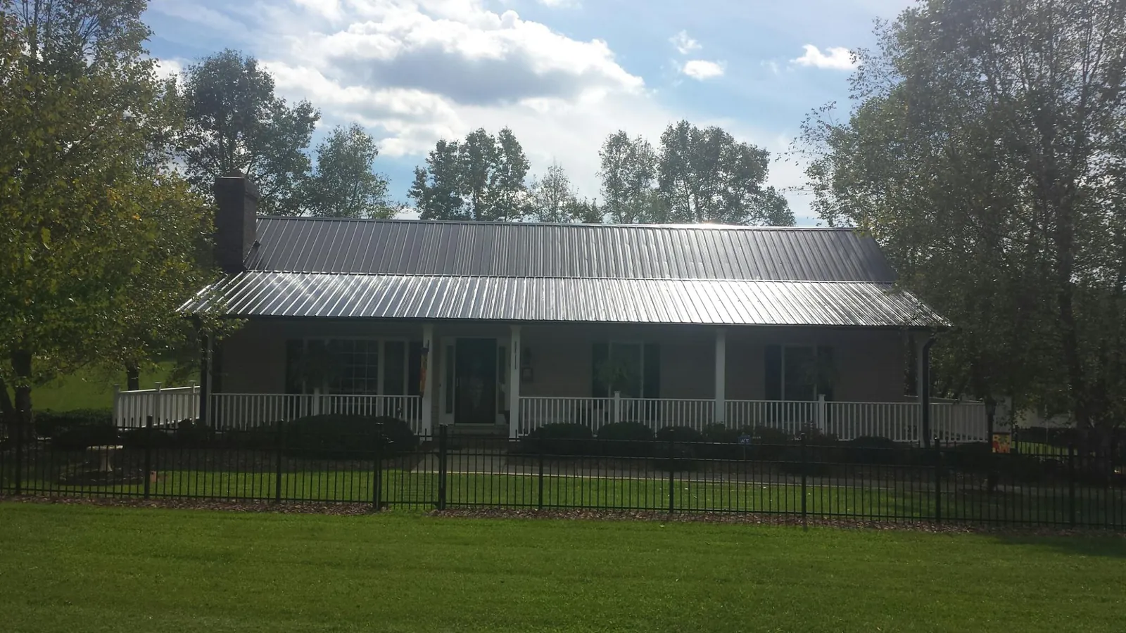 Gray metal roof on a brick ranch with a full width front porch — Gutter Guard Installation work by our crew in Gates